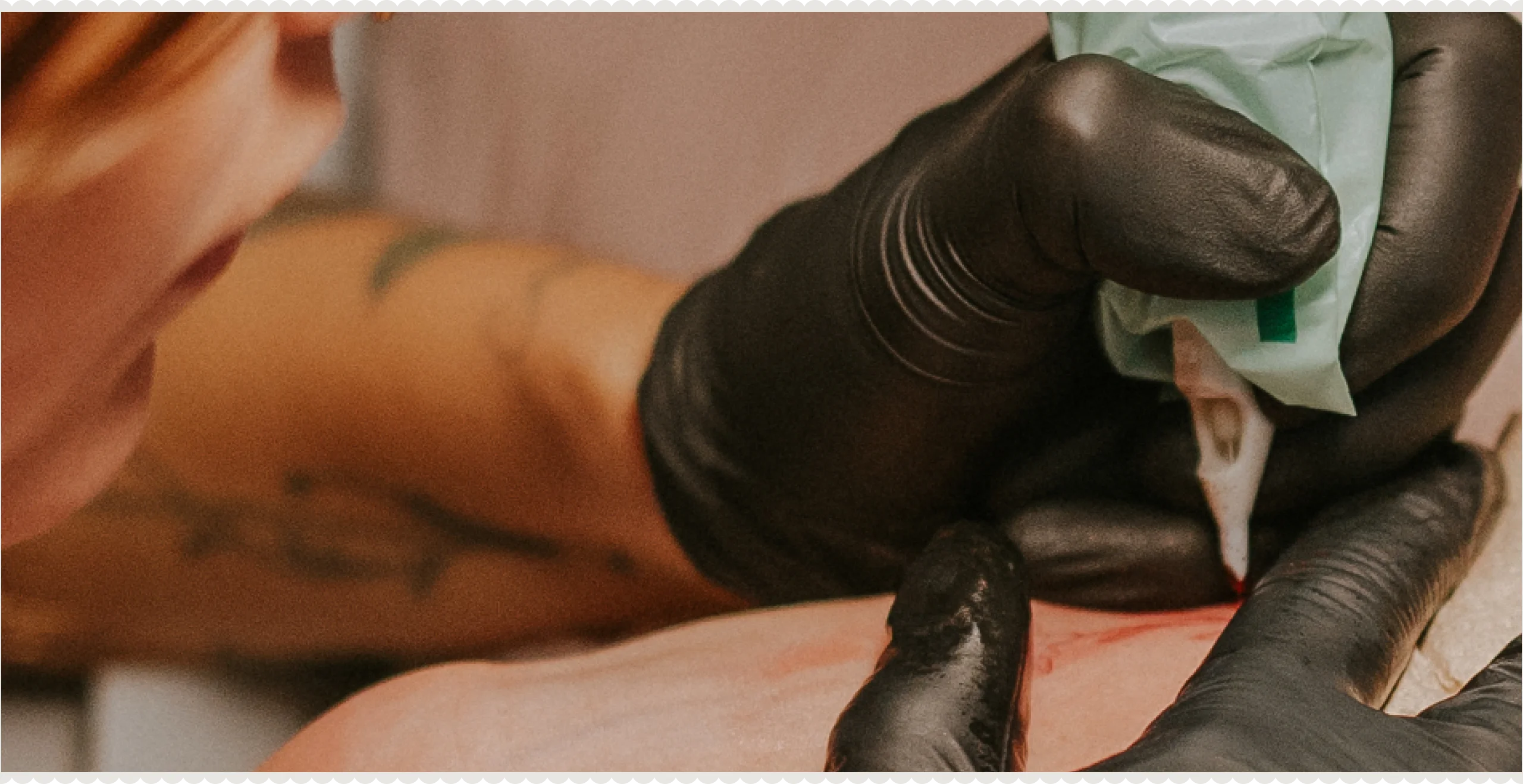 Tattoo artist working with gloves on a fine-line botanical piece
